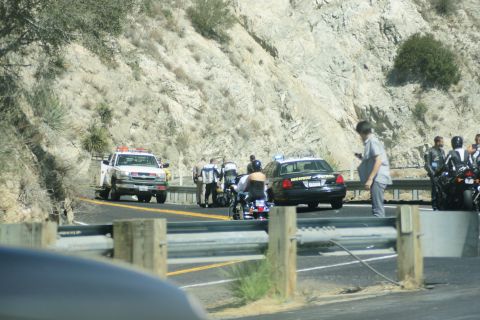 1995 Ford Taurus - A Highway Patrol car and a tow truck are stopped on the side of a road, with several people and motorcycles present.
