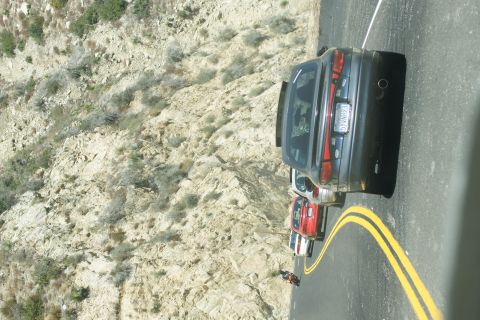 1995 Ford Taurus - A line of cars, including a dark sedan, travels along a mountain road.
