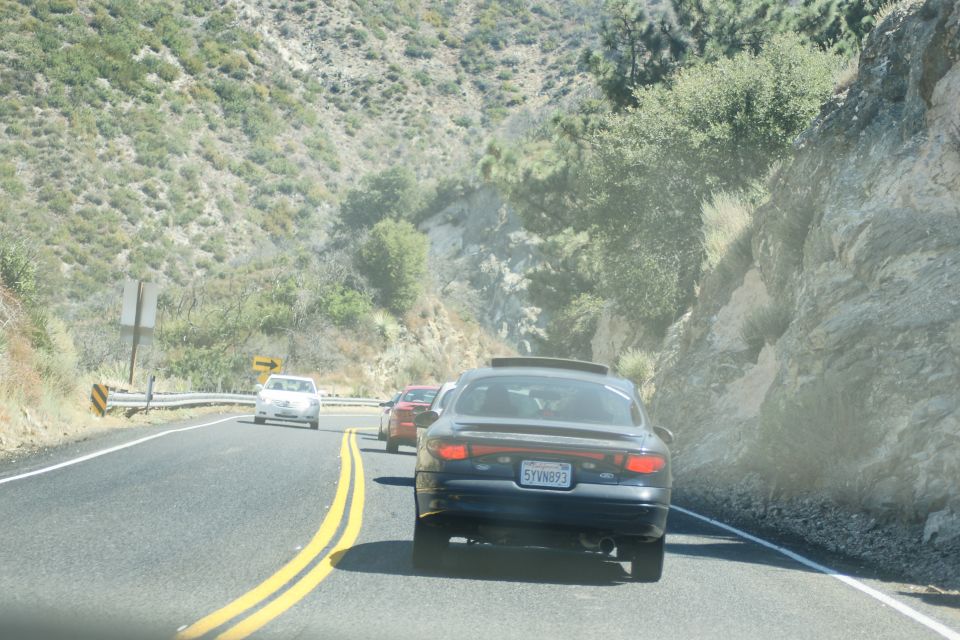 Dark sedan with a sunroof on a mountain road, license plate 5TVN893