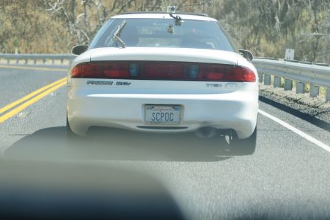 1995 Ford Taurus - Rear view of a white 1995 Ford Taurus driving on a highway with a California license plate.