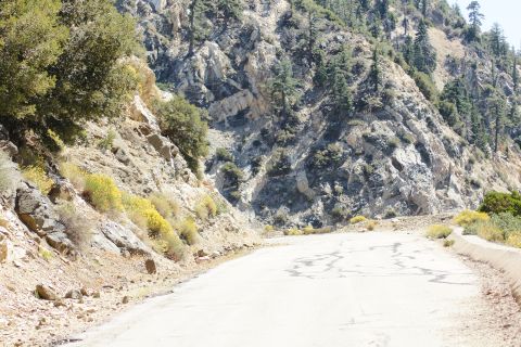 1995 Ford Taurus - A paved road curves through a mountain landscape with dry brush and rocky cliffs.
