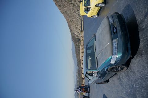 1995 Ford Taurus - A green 1995 Ford Taurus sedan is parked on a roadside with a yellow car behind it.