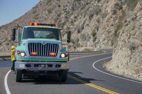 1995 Ford Taurus - A green tow truck with emergency lights illuminates the road as it travels on a winding mountain highway.