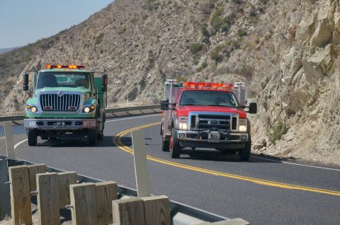 1995 Ford Taurus - Two emergency response vehicles, a green International and a red Ford, travel along a scenic mountain highway.