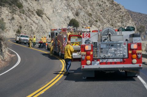 1995 Ford Taurus - Emergency responders and fire trucks are gathered on the side of a winding mountain road.