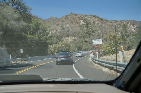 1995 Ford Taurus - A view from inside a vehicle shows two cars on a winding road through a canyon on a clear day.