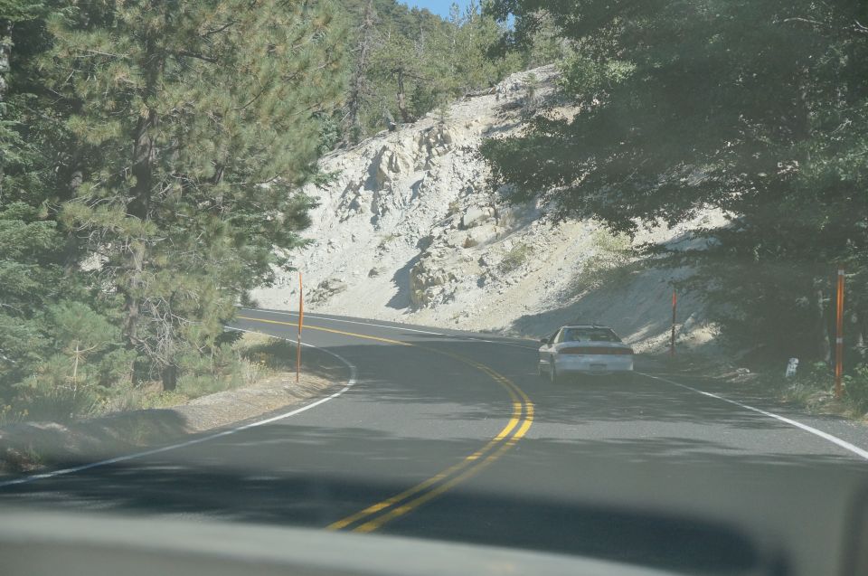 Silver sedan driving on a winding road, seen from behind
