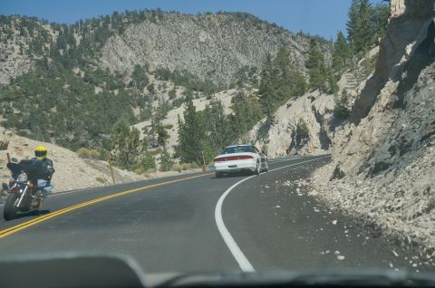 1995 Ford Taurus - A motorcycle and a white car travel on a scenic mountain highway.
