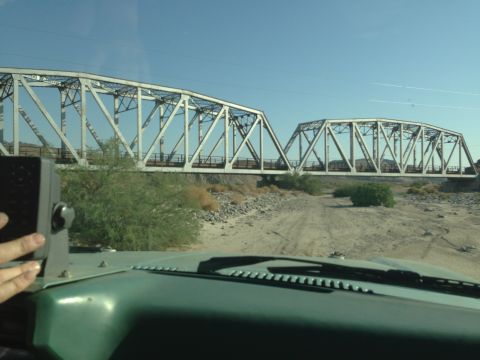 1986 Ford Bronco - View from inside a vehicle approaching a large, multi-span metal truss bridge under a clear blue sky.