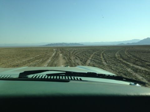 1986 Ford Bronco - Desert landscape with tire tracks seen from inside a vehicle. "SUPERMOTORS" logo is visible.