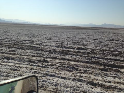 1986 Ford Bronco - The vast, textured expanse of a dry lake bed stretches towards distant mountains under a clear sky.