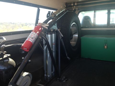 1986 Ford Bronco - The interior of a vehicle is equipped with a spare tire, fire extinguisher, and a locked green toolbox.