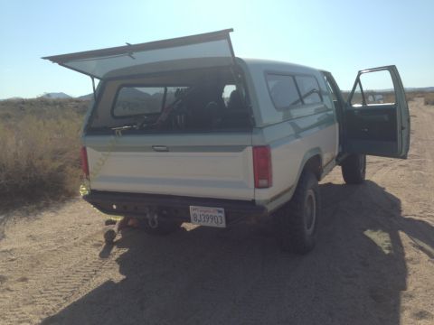 1986 Ford Bronco - 1986 Ford Bronco with tailgate and driver door open, parked in a desert landscape.