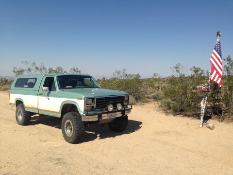 1986 Ford Bronco - This SUV is parked in a dry, arid environment with sparse vegetation and a clear blue sky overhead.