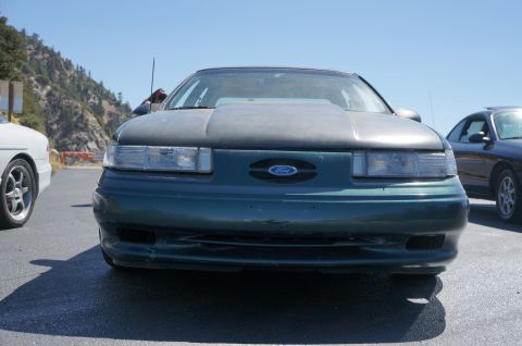 1995 Ford Taurus - Front view of a green 1995 Ford Taurus, distinguished by its grey hood and prominent Ford emblem.