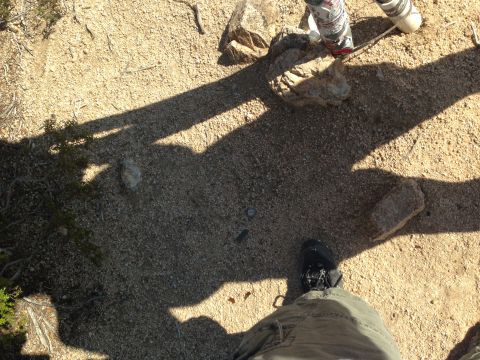 1986 Ford Bronco - View of the ground from a person's perspective, showing shadows and desert terrain.