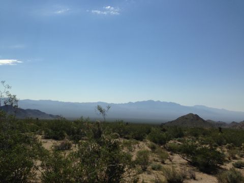 1986 Ford Bronco - A wide view of a desert landscape with mountains in the background and scrub brush in the foreground.