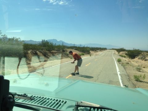 1986 Ford Bronco - View from inside a 1986 Ford Bronco on a desert road, with a man standing in the lane ahead.