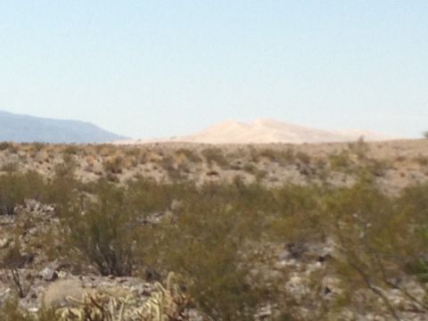 1986 Ford Bronco - Desert landscape with scrub brush, distant mountains, and sand dunes under a clear sky.