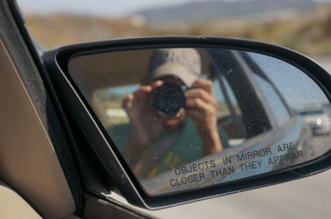 1995 Ford Taurus - A person captures their own reflection while driving, with a warning about mirror distance visible.