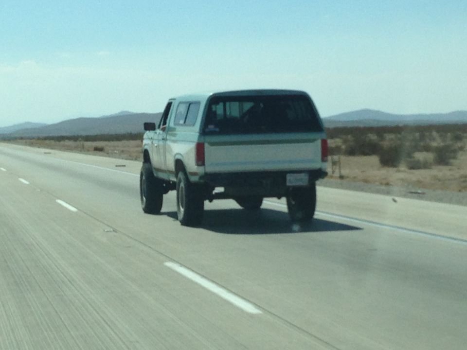 Rear view of a lifted white and teal SUV on a highway