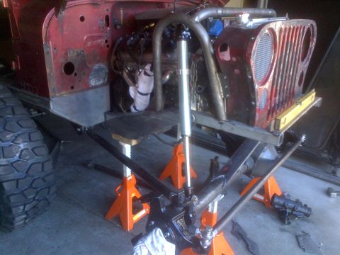 1985 Jeep CJ7 - Front view of a red Jeep CJ undergoing modifications, with its engine and suspension exposed.
