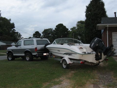 1994 Ford Bronco - Two-tone silver Ford Bronco hitched to a trailer carrying a white Sea Ray bowrider boat with outboard.