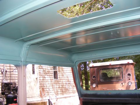 Teal interior roof with skylight, looking out at a brown truck's rear