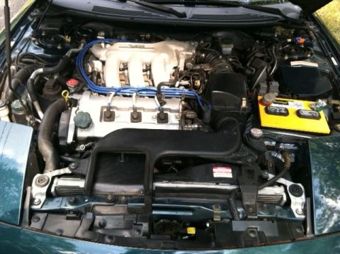 1997 Ford Probe - The engine bay of a green vehicle is shown, the V6 engine and associated components.