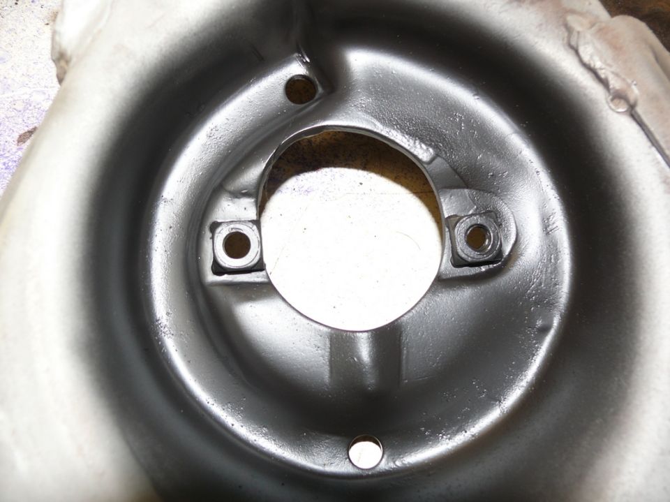 Close-up of a metal automotive part with a central opening and two mounting points