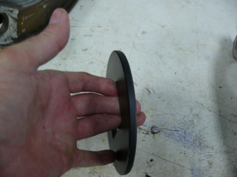 1976 Chevrolet Corvette - A hand holds a black disc, possibly a car part, against a textured surface.