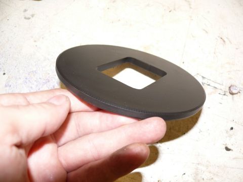 1976 Chevrolet Corvette - This black oval part has a square hole in the center and is being held by a person's hand.