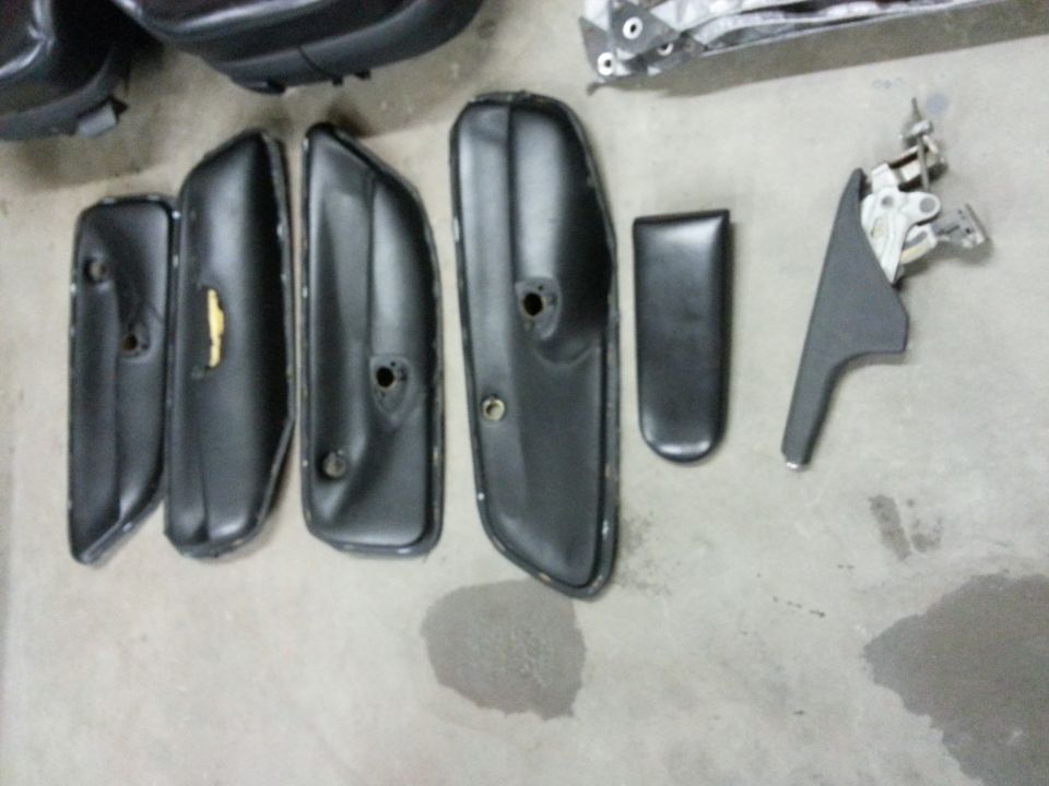 Several black car door panels and trim pieces laid out on a concrete floor