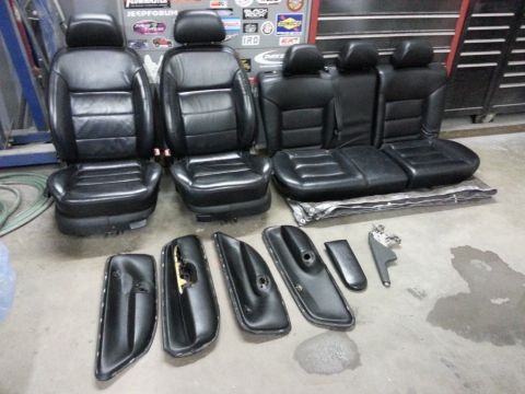 2002 Volkswagen Jetta - A set of black leather car seats and interior door panels are laid out on the floor.