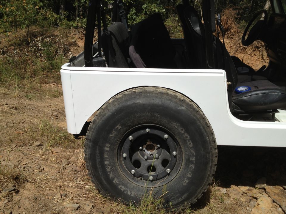 White Jeep rear quarter panel and large tire with black rim