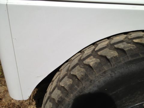 2000 Jeep TJ - White vehicle fender and a large off-road tire are shown in this close-up shot.