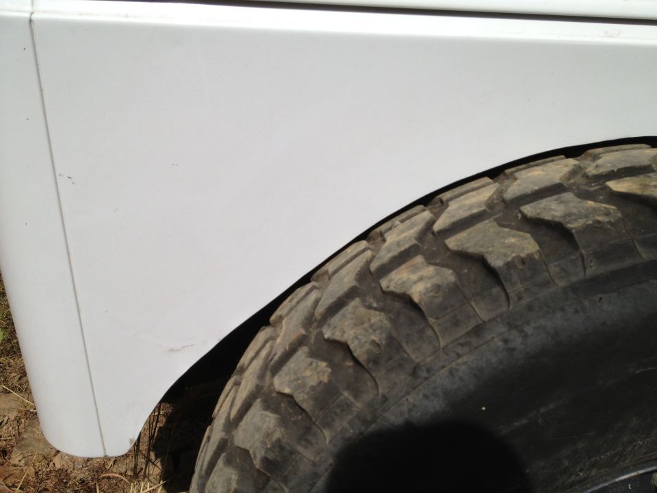 Close-up of a white vehicle's front fender and a large off-road tire
