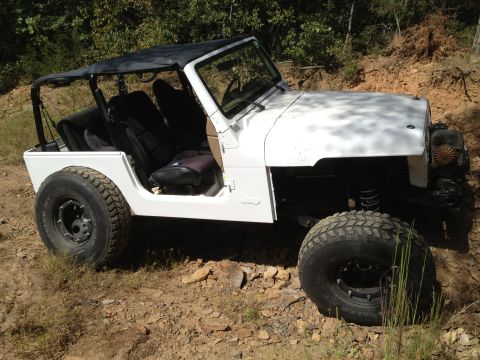 2000 Jeep TJ - This Jeep Wrangler is parked on a rocky, wooded trail with its doors off and soft top down.
