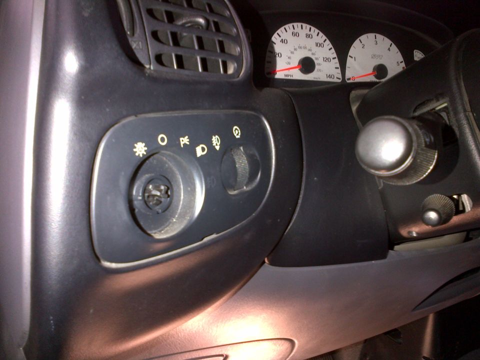 Dashboard interior with ignition, headlight controls, and speedometer visible. The speedometer reads up to 140 mph