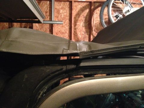 2005 Jeep Wrangler - A close-up view of a damaged soft top on a vehicle, revealing a tear and water damage.