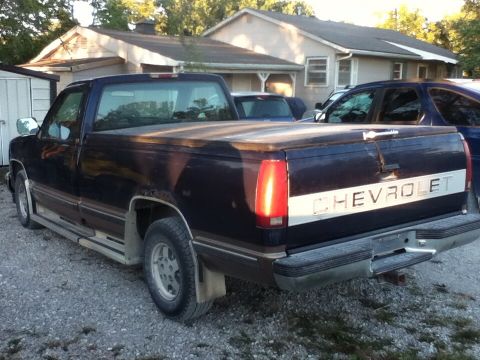 2006 Ford E350 - Dark blue Chevrolet C/K pickup truck parked in a gravel driveway with a tonneau cover on the bed.