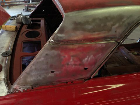 1964 Ford Fairlane - Close-up of a red car's body panel undergoing repair, revealing bare metal and structural components.