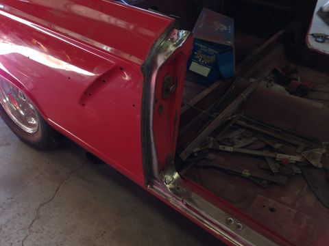 1964 Ford Fairlane - The interior of a red car is shown with the door panel removed, revealing the window mechanism and other components.