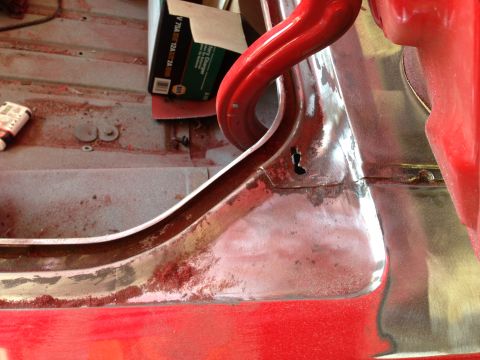1964 Ford Fairlane - Close-up of a red vehicle's interior door frame and floor pan, showing sanding dust and a box of sandpaper, possibly, sandpaper.