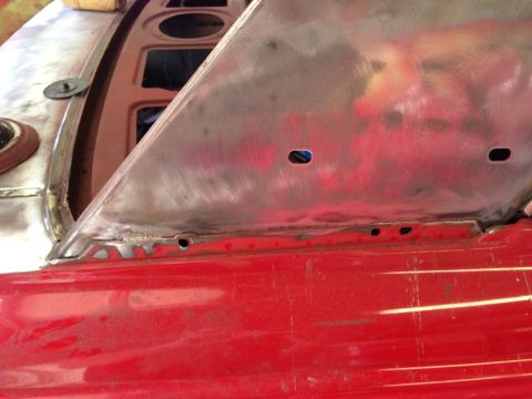 1964 Ford Fairlane - Metal body panel repair in progress on a red vehicle, with visible welds and sanded areas.