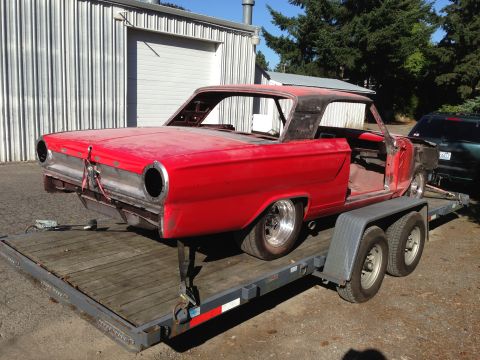 1964 Ford Fairlane - The body of a 1964 Ford Fairlane, stripped down and red, is transported on a trailer.