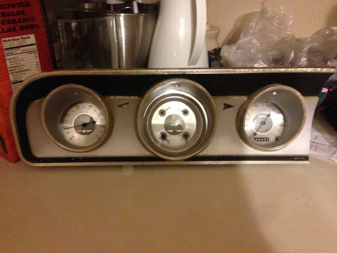 1964 Ford Fairlane - A vintage car's instrument cluster, a speedometer and two other gauges, sits on a counter.