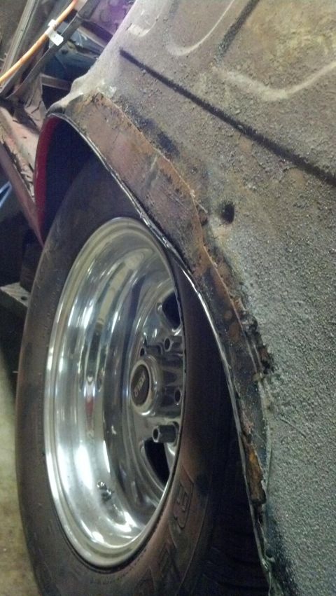 1964 Ford Fairlane - Close-up of a rusty wheel well and chrome wheel on a vehicle.