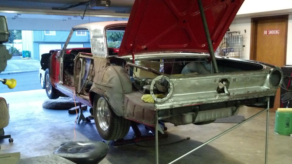 1964 Ford Fairlane body on jack stands with hood and trunk open, undergoing restoration