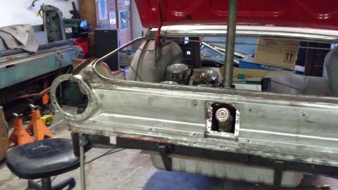 1964 Ford Fairlane - The rear section of a car is undergoing repairs in a workshop, with the trunk lid open.